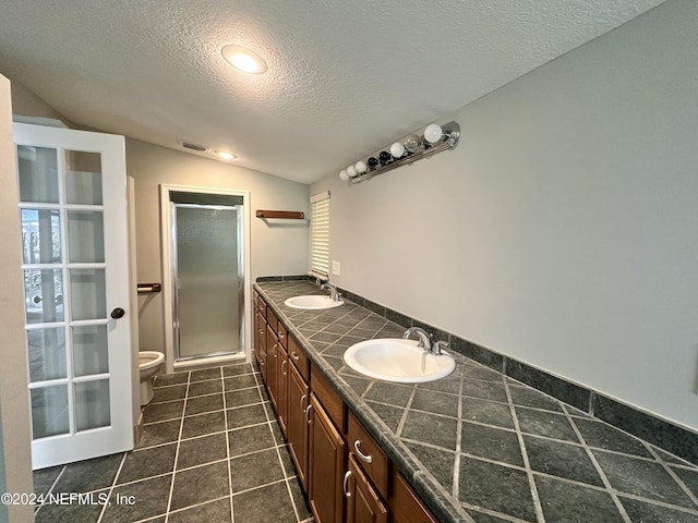 bathroom with a textured ceiling, visible vents, a shower stall, and a sink