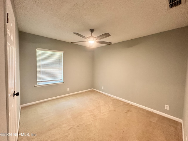 carpeted empty room with visible vents, a textured ceiling, baseboards, and ceiling fan
