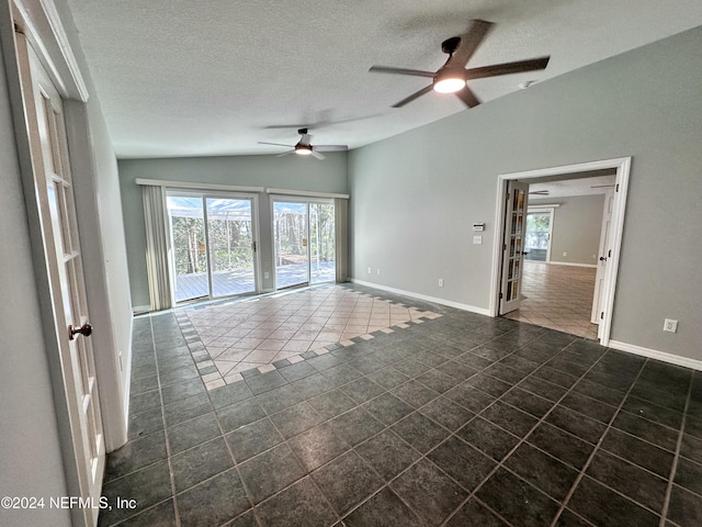 unfurnished room with ceiling fan, a wealth of natural light, and dark tile patterned flooring