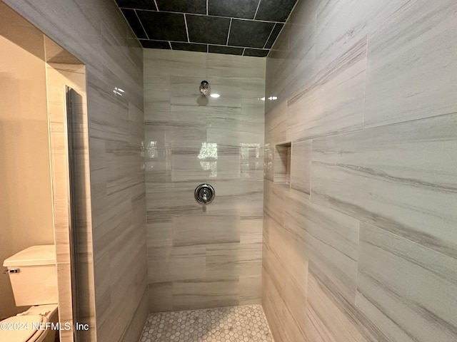 bathroom with toilet, tile patterned floors, and tiled shower