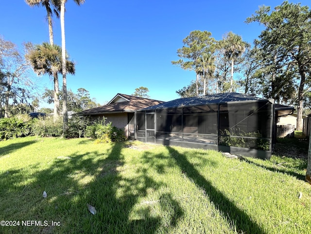 back of property featuring a sunroom and a lawn