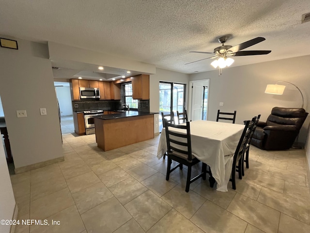 tiled dining room with ceiling fan, a textured ceiling, and sink