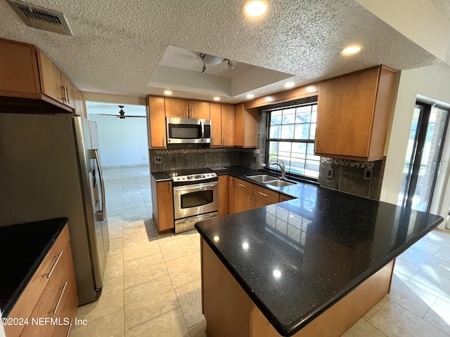 kitchen featuring a textured ceiling, a tray ceiling, stainless steel appliances, and sink