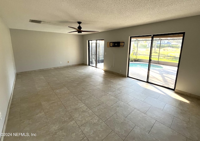 tiled spare room with a textured ceiling and ceiling fan