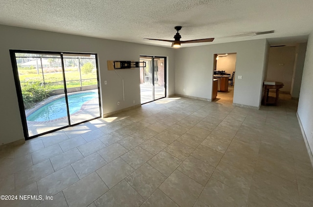 empty room with ceiling fan, a textured ceiling, and light tile patterned floors