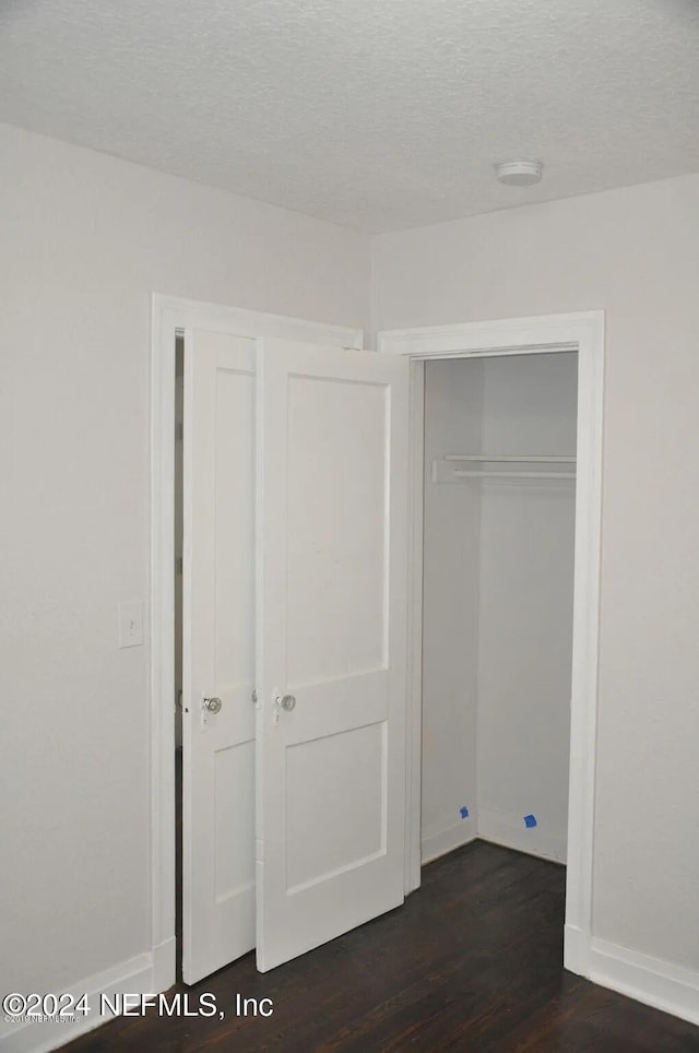 unfurnished bedroom featuring dark hardwood / wood-style floors and a textured ceiling