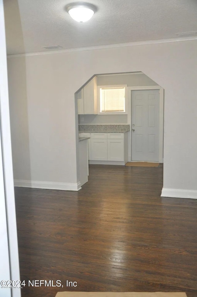 unfurnished room featuring crown molding, a textured ceiling, and dark hardwood / wood-style flooring