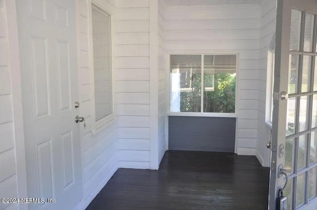 interior space with wooden walls and dark hardwood / wood-style flooring