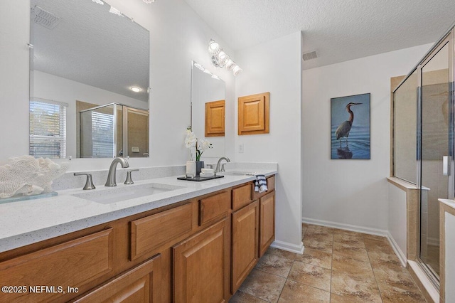 bathroom featuring vanity, a textured ceiling, and a shower with shower door