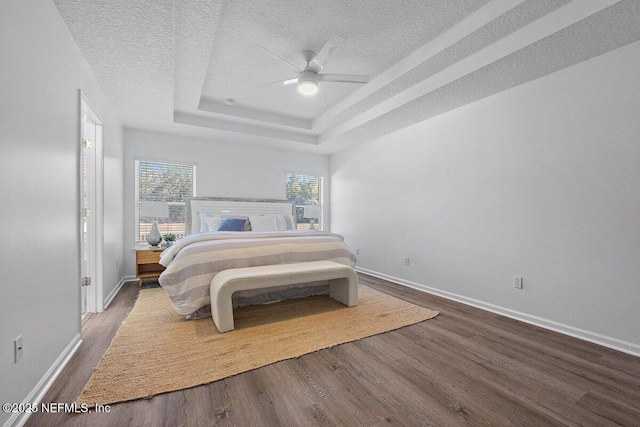 bedroom featuring hardwood / wood-style flooring, ceiling fan, a raised ceiling, and a textured ceiling