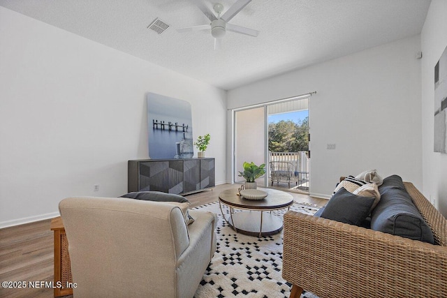 living room featuring ceiling fan, wood-type flooring, and a textured ceiling