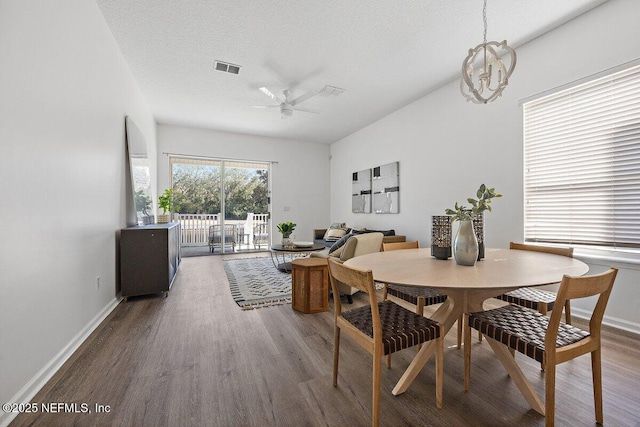 dining space with ceiling fan with notable chandelier, wood-type flooring, and a textured ceiling