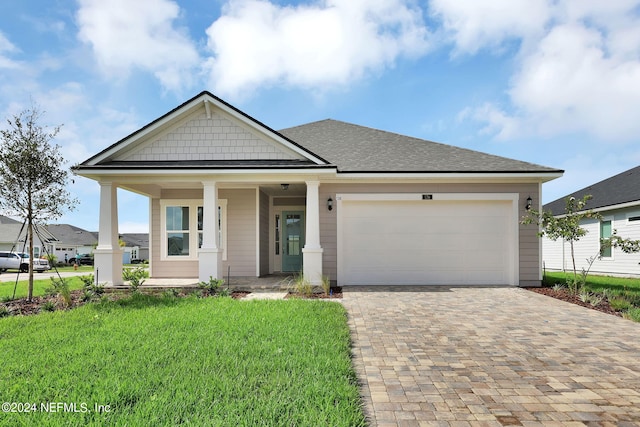 view of front of property featuring a front yard, a porch, and a garage