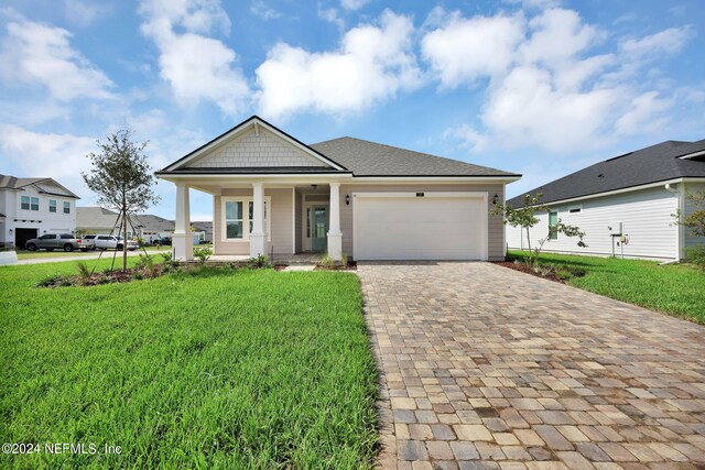 view of front of house featuring covered porch, a garage, and a front yard