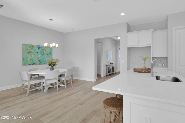 dining room featuring sink, an inviting chandelier, and light wood-type flooring