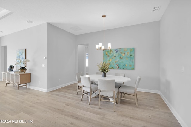 dining space featuring light wood-type flooring and an inviting chandelier