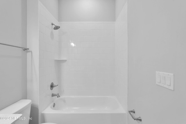 bathroom with tiled shower / bath combo and toilet