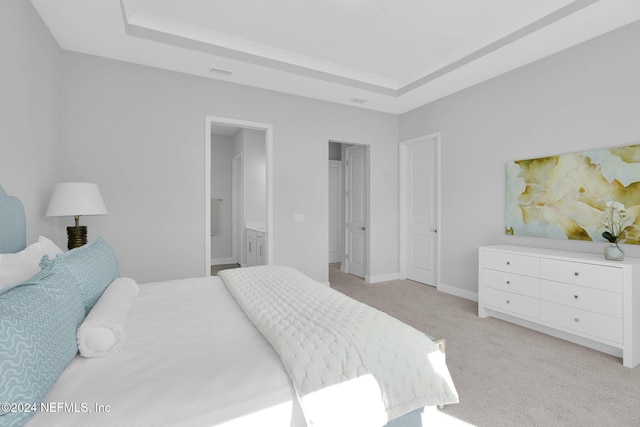 carpeted bedroom with ensuite bathroom and a raised ceiling