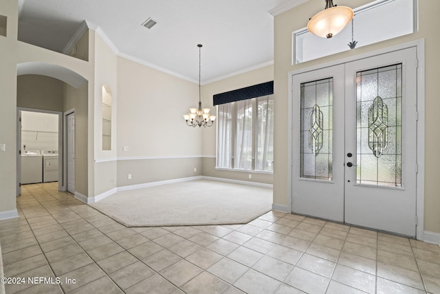 foyer featuring french doors, crown molding, light tile patterned floors, a notable chandelier, and washing machine and clothes dryer