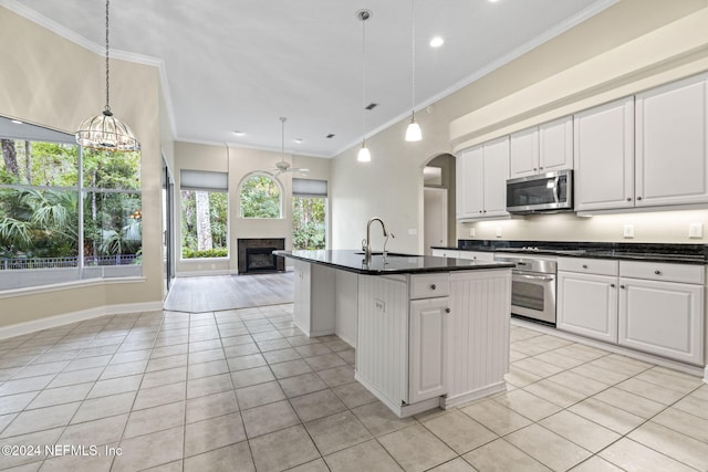 kitchen featuring white cabinetry, hanging light fixtures, a kitchen island with sink, and stainless steel appliances