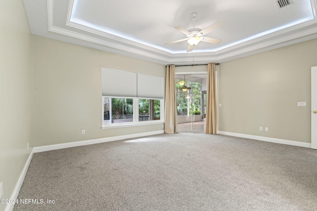 carpeted spare room with ceiling fan, crown molding, and a tray ceiling