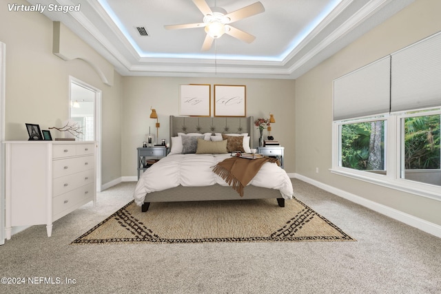 bedroom with light colored carpet, ceiling fan, and a raised ceiling