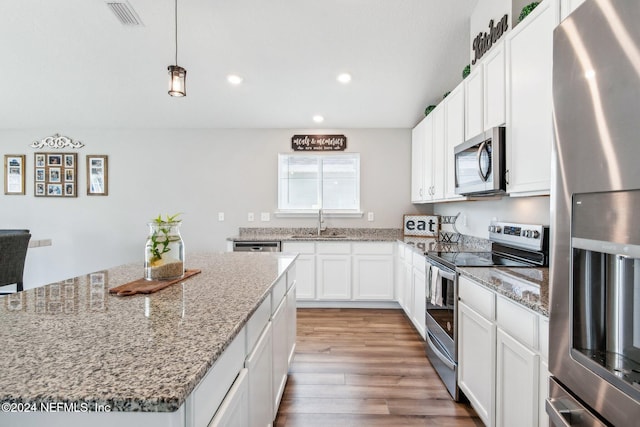 kitchen featuring white cabinets, hanging light fixtures, light wood-type flooring, stainless steel appliances, and a center island