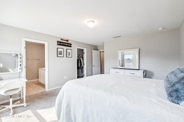 carpeted bedroom with a spacious closet, ensuite bathroom, and a closet