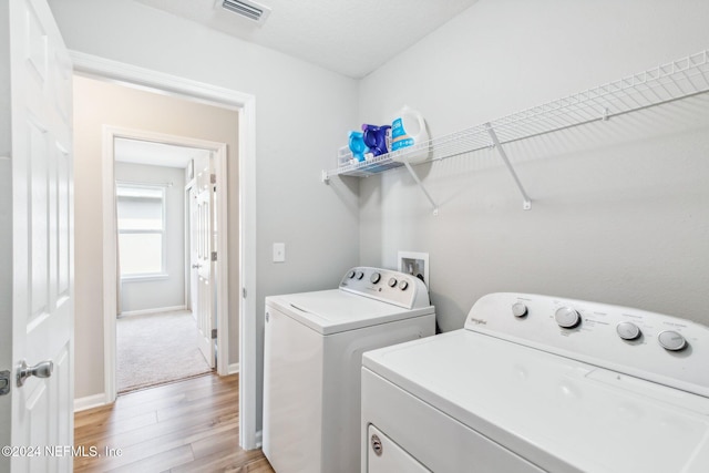 clothes washing area featuring light hardwood / wood-style floors and washing machine and clothes dryer