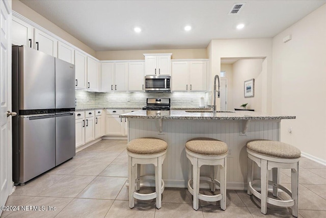 kitchen featuring stainless steel appliances, sink, a center island with sink, and white cabinets