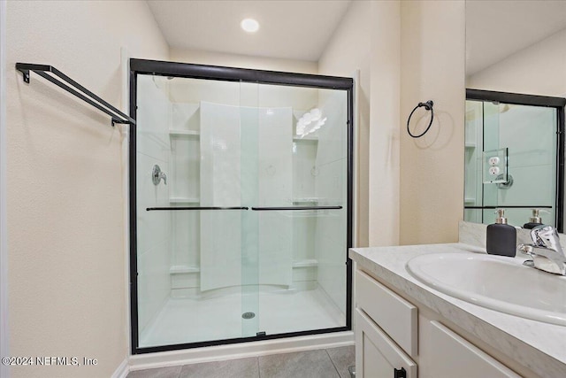 bathroom featuring vanity, a shower with shower door, and tile patterned flooring