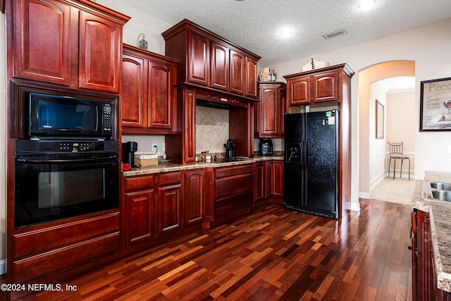 kitchen with black appliances, a textured ceiling, dark hardwood / wood-style flooring, light stone counters, and decorative backsplash