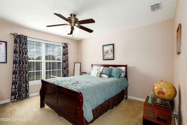 bedroom with a textured ceiling, light colored carpet, and ceiling fan