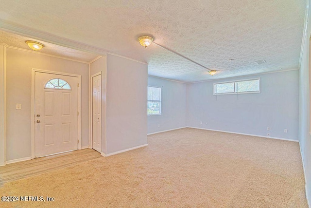 carpeted foyer entrance with a textured ceiling and ornamental molding