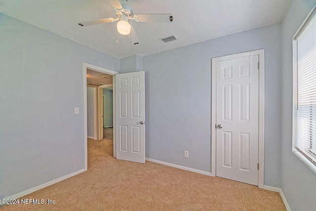 unfurnished bedroom featuring light colored carpet and ceiling fan