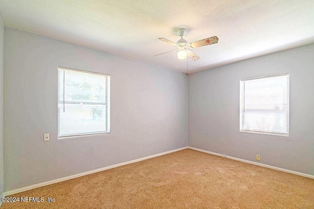 carpeted empty room featuring ceiling fan and a wealth of natural light