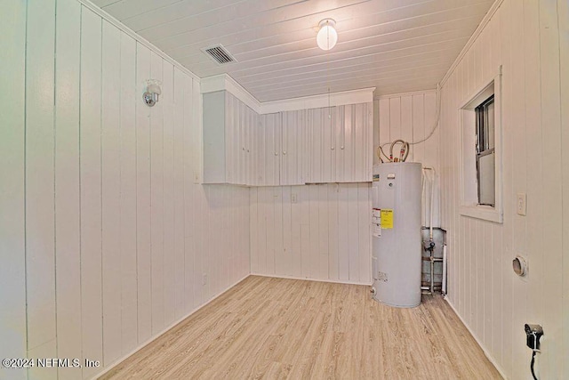 laundry area featuring crown molding, light wood-type flooring, wood walls, and water heater