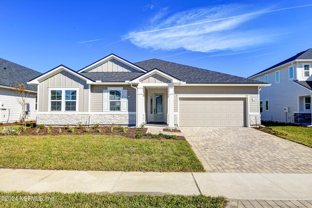 2523 Trailmark Dr, Saint Augustine, FL 32092 - view of front facade with board and batten siding, stone siding, decorative driveway, a front yard, and a garage