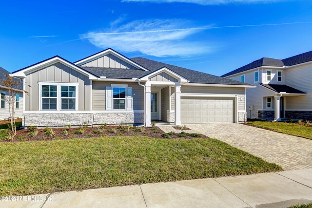 2523 Trailmark Dr, Saint Augustine, FL 32092 - view of front of house featuring a front lawn, driveway, stone siding, board and batten siding, and an attached garage