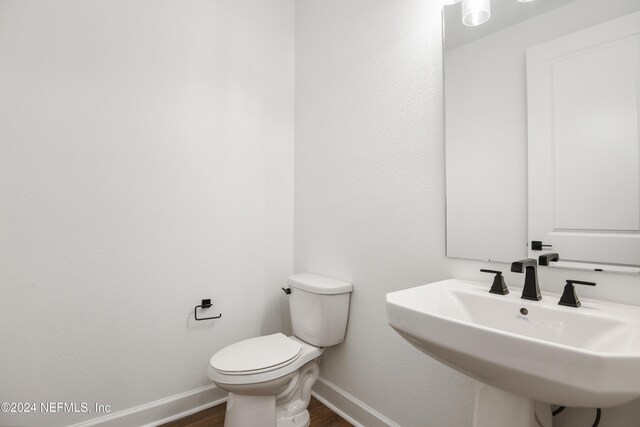 2523 Trailmark Dr, Saint Augustine, FL 32092 - half bath featuring toilet, a sink, wood finished floors, and baseboards