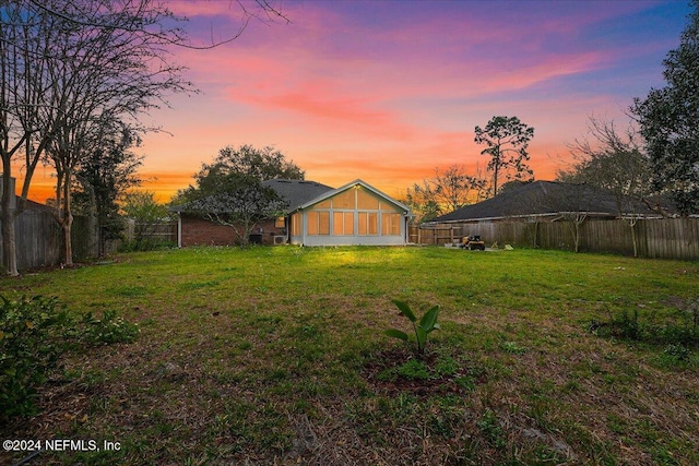 yard at dusk featuring a sunroom