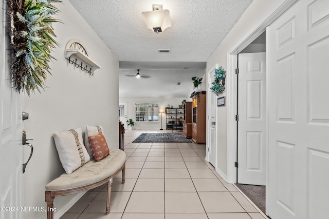 corridor featuring a textured ceiling and light tile patterned floors