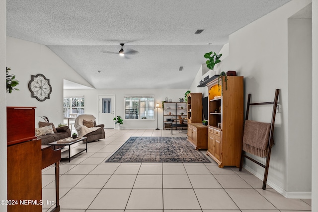 living room with lofted ceiling, a textured ceiling, light tile patterned floors, and ceiling fan