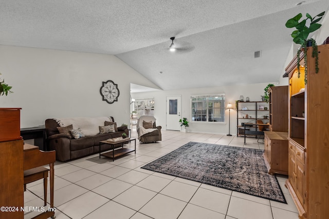 living room featuring ceiling fan, a textured ceiling, light tile patterned floors, and vaulted ceiling