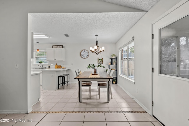 tiled dining room featuring a wealth of natural light, a textured ceiling, and a notable chandelier