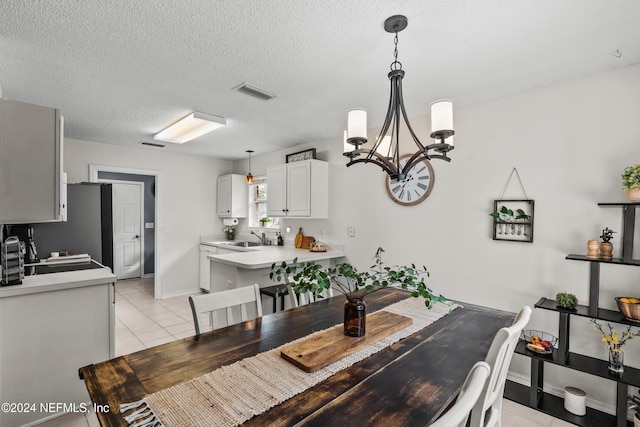 dining space with light tile patterned floors, a textured ceiling, sink, and a notable chandelier