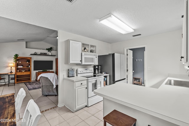 kitchen featuring vaulted ceiling, a textured ceiling, light tile patterned floors, white cabinetry, and white appliances