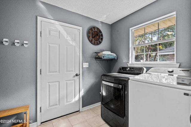 laundry room with washer and clothes dryer, a textured ceiling, and light tile patterned floors