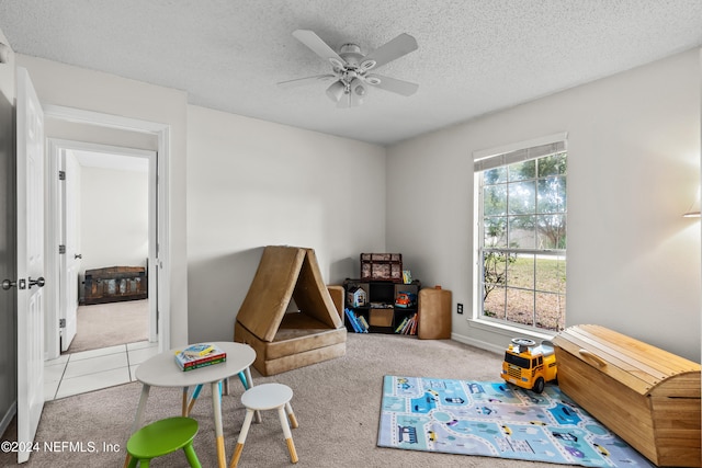 playroom featuring a textured ceiling, light colored carpet, and ceiling fan