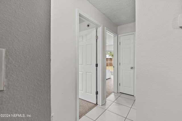 hallway with a textured ceiling and light carpet